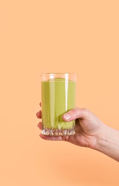 Hand holding green smoothie glass