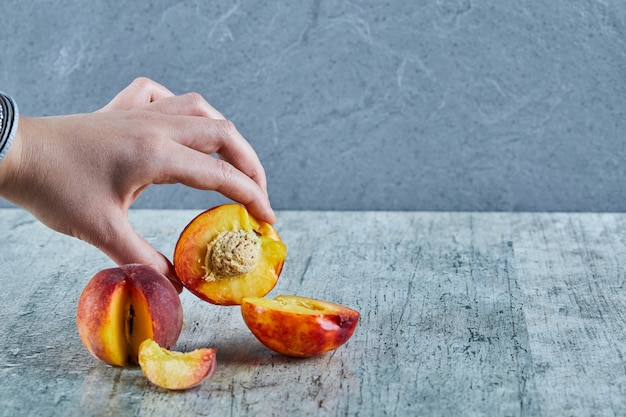 Hand holding half cut of peach on marble surface