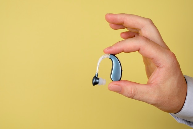 Hand holding hearing aids with copy space