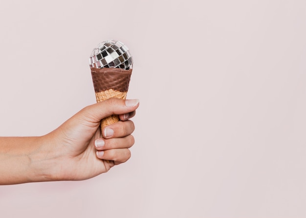 Free photo hand holding ice cream cone with disco ball