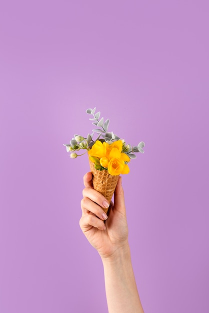 Free photo hand holding ice cream cone with flowers