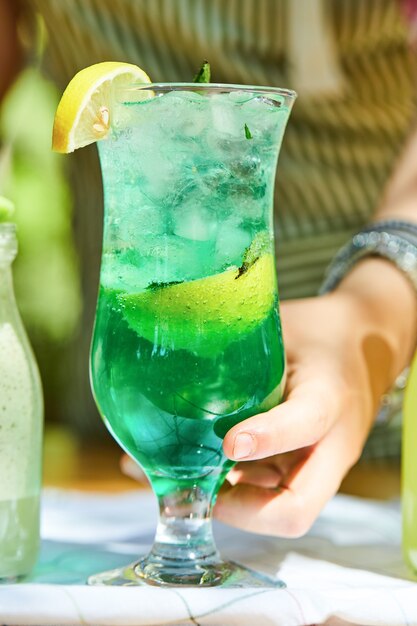 Hand holding a lemonade on wooden table.