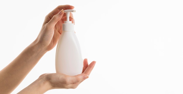 Free photo hand holding liquid soap bottle with copy space