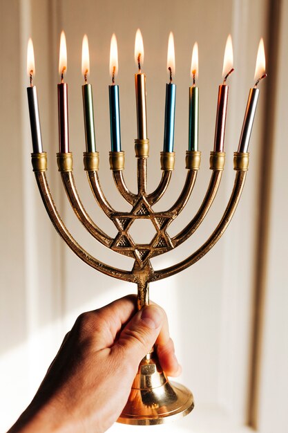 Hand holding menorah with candles burning
