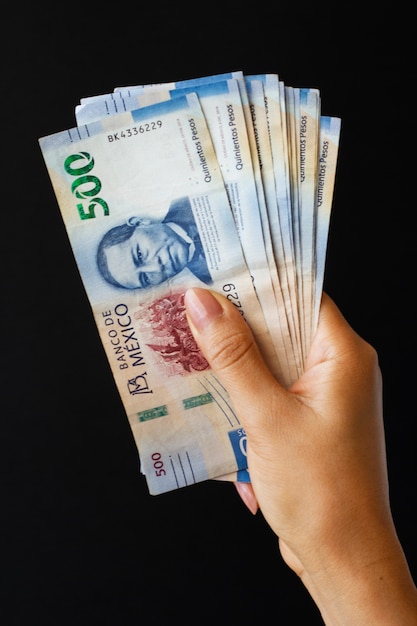 Free photo hand holding mexican banknotes