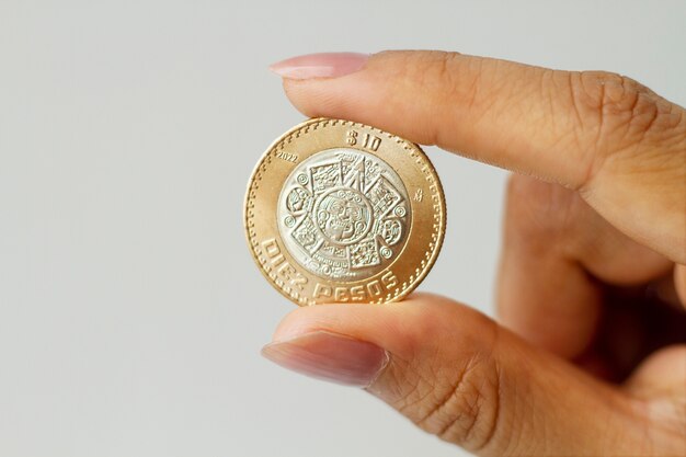 Рука держит мексиканскую монету крупным планом