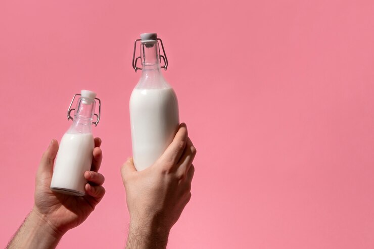Free Photo hand holding milk bottle still life
