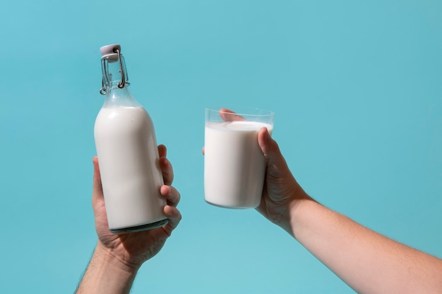 Foto gratuita la mano che tiene la bottiglia di latte è una natura morta