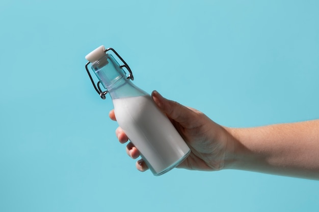 Free photo hand holding milk bottle still life