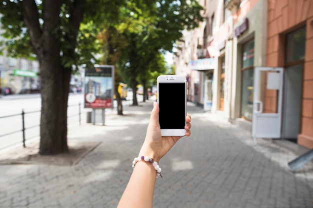 Free photo hand holding mobile with blank screen at street