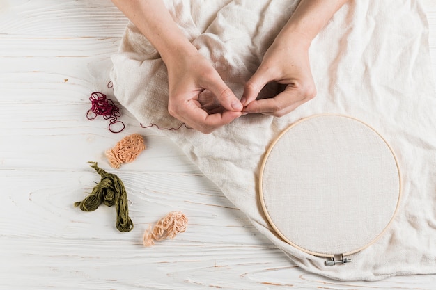 Free photo hand holding needle and thread on tambour frame