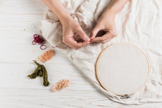 Hand holding needle and thread on tambour frame