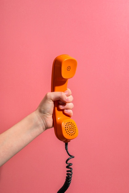 Рука старый телефон с розовым фоном