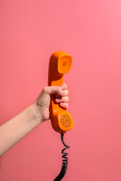 hand holding old phone with pink background