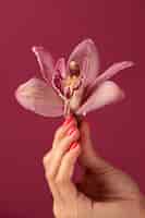 Бесплатное фото Рука держит орхидею сбоку