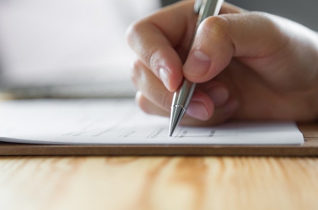 Hand holding a pen on a paper