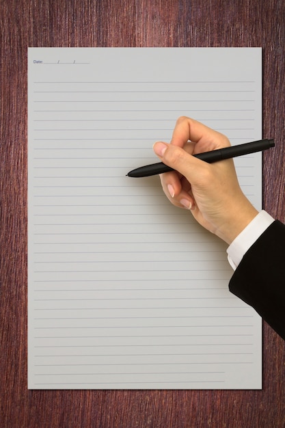 Hand holding a pen on a striped paper