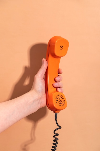 Free photo hand holding phone with orange background