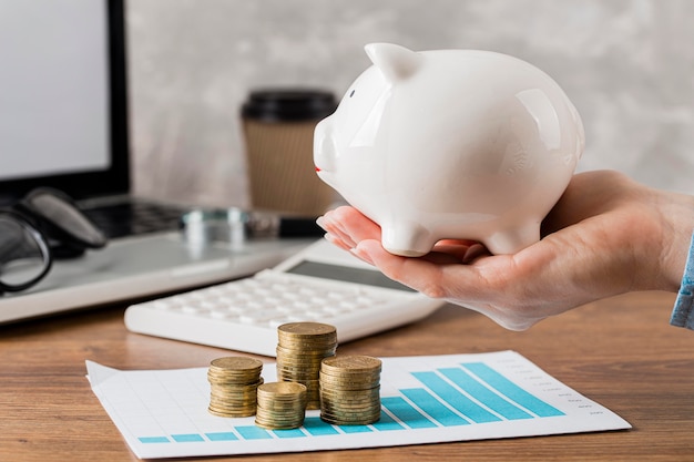 Free photo hand holding piggy bank with growth chart and coins