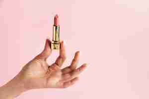 Free photo hand holding pink lipstick close up
