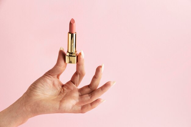 Hand holding pink lipstick close up