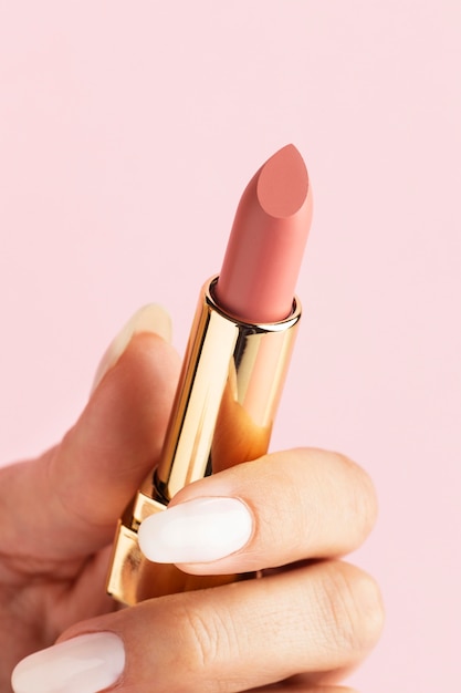 Free photo hand holding pink lipstick