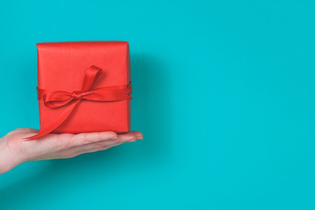 Hand holding a red gift on a blue background