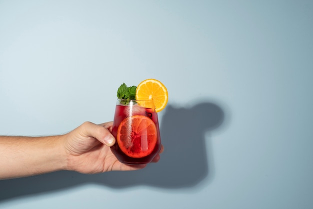 Hand holding refreshing hibiscus ice tea in clear glass container