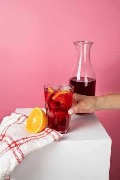 Free photo hand holding refreshing hibiscus ice tea in clear glass container