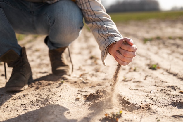 Рука держит песок в сельской местности