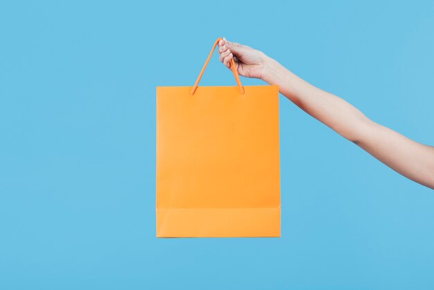 Hand holding shopping bag on plain background