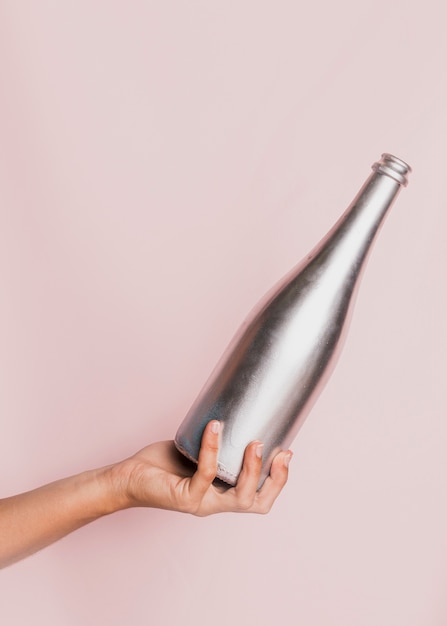 Free photo hand holding silver champagne bottle