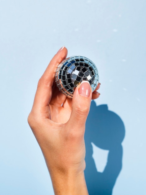 Free photo hand holding silver disco globe