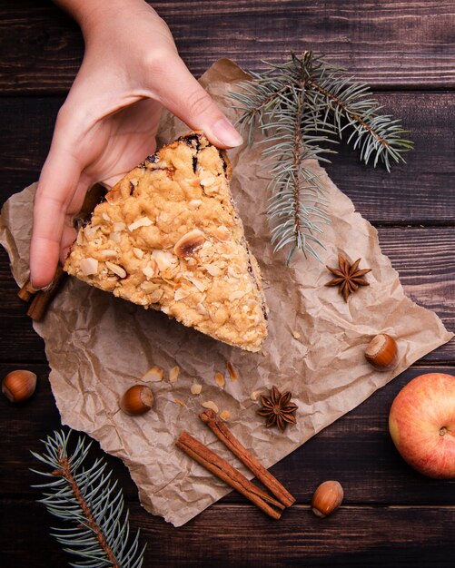 Hand holding slice of cake with cinnamon sticks