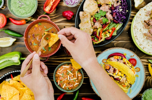 hand holding spoon and nacho near mexican food
