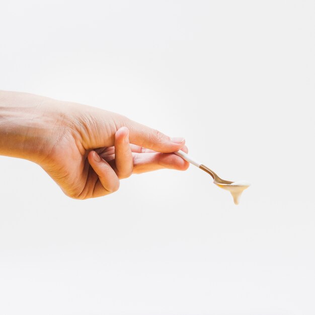 Hand holding spoon with cream 