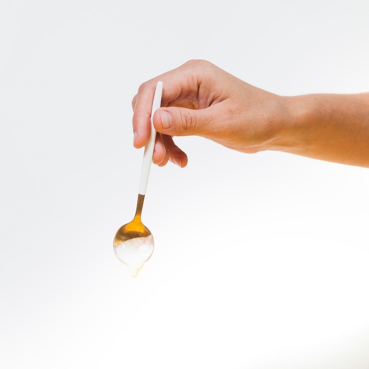 Free Photo hand holding spoon with falling cream