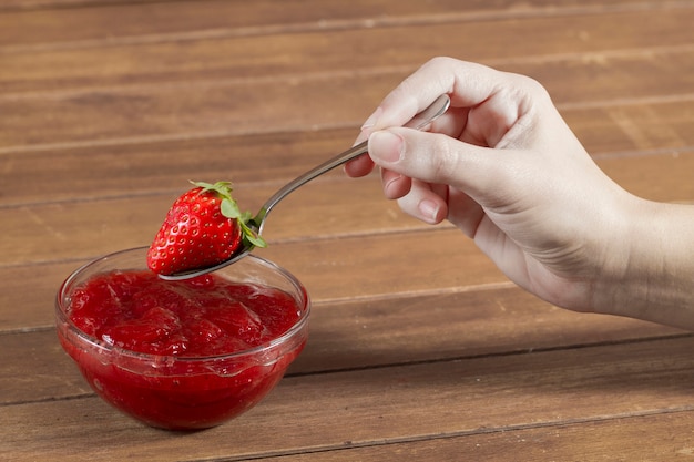 Hand holding a spoon with a strawberry