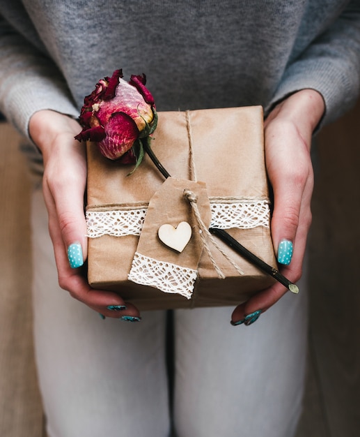 Hand holding square brown package with a flower