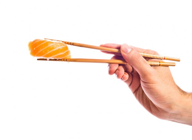 hand holding sushi with chopsticks