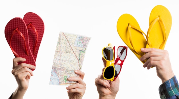 Hand holding travel items with flip-flops and sunglasses