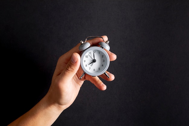 Free photo hand holding a vintage little clock