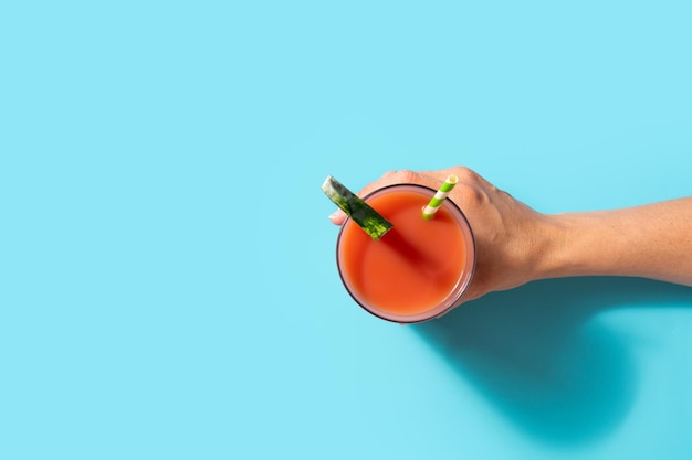 Hand holding watermelon juiceon blue background copy space