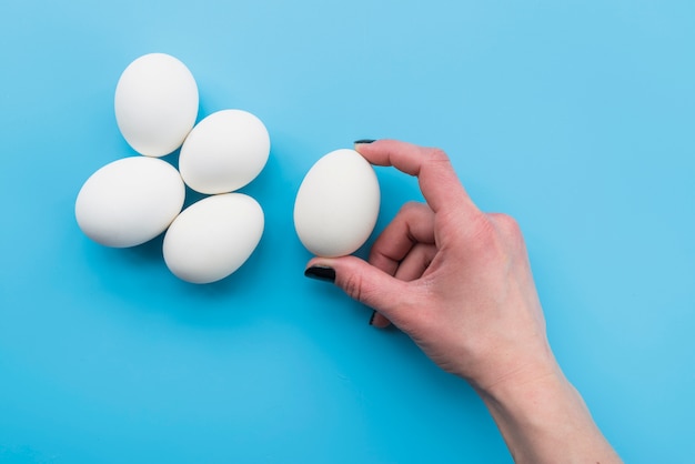 Hand holding white egg with fingers 