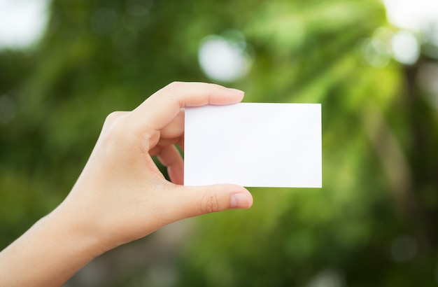 Free photo hand holding a white paper with the background defocused