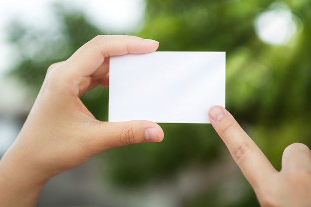 Free photo hand holding a white paper with the background defocused