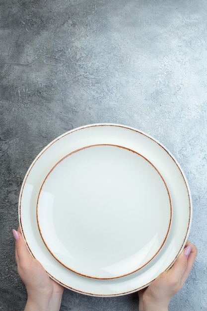 Hand holding white plates on gray surface with distressed coarse-grained gradient surface