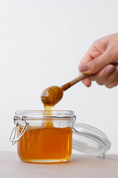 hand holding wooden honey dipper from honey jar