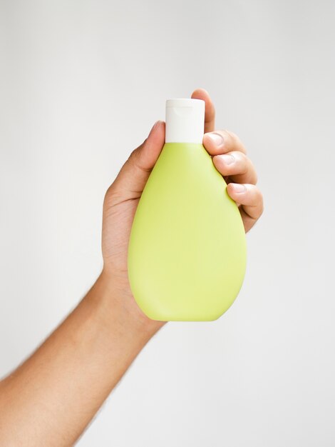 Hand holding yellow lotion bottle mock-up