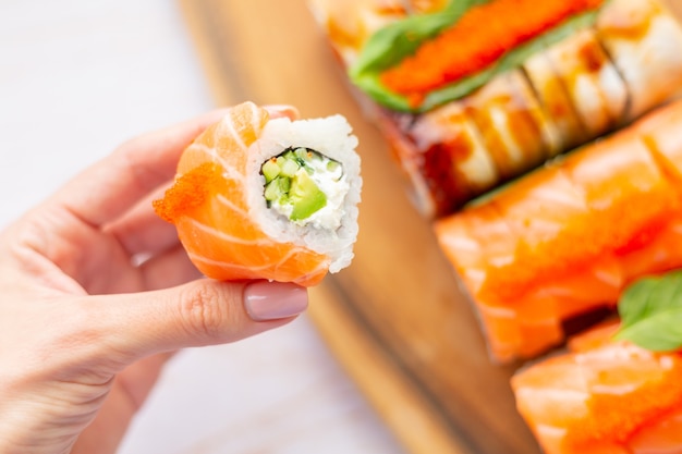 Hand holds roll with salmon and cream cheese